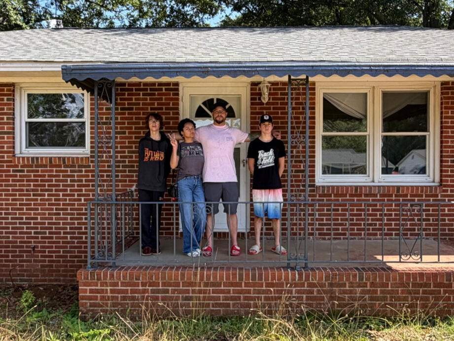 Our first Do Well Housing home Eli with his wife and two sons on the porch of the first Do Well Housing home